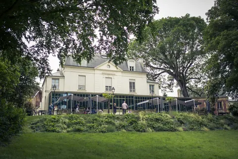 Le bâtiment et sa verrière vus depuis la pelouse du parc arboré